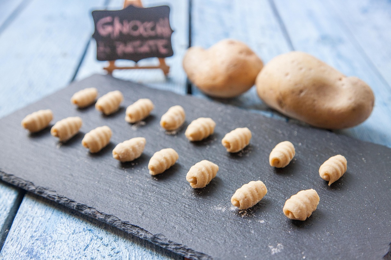 Gnocchi di patate freschi su un piano di lavoro con ingredienti pronti per la preparazione.