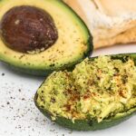 Salsa di avocado cremosa servita in una ciotola, guarnita con lime e coriandolo fresco.