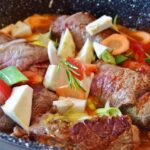 Cottura lenta di un piatto gourmet, evidenziando ingredienti freschi e aromi ricchi.