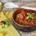 Preparazione di un ragù saporito con ingredienti freschi e un pentolone sul fuoco.