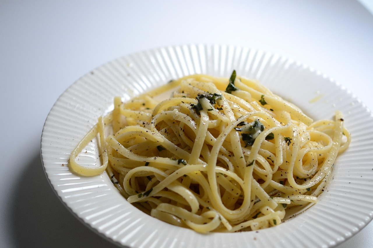 Pasta al limone con crema vellutata e scorza di limone grattugiata, servita in un piatto bianco.