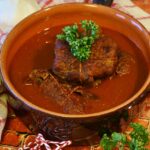 Brasato al vino rosso servito su un piatto, guarnito con erbe fresche e contorni.