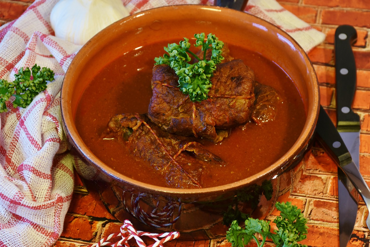 Brasato al vino rosso servito su un piatto, guarnito con erbe fresche e contorni.