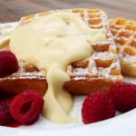 Ciotola di crema pasticcera densa e vellutata, guarnita con vaniglia e scorza di limone.