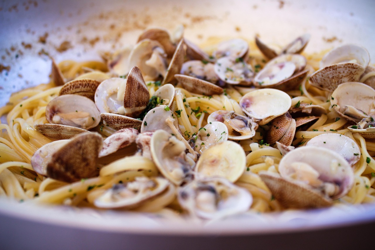 Piatto di pasta con vongole e bottarga, decorato con prezzemolo fresco.